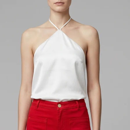 Person wearing a white halter top and red pants on a gray background